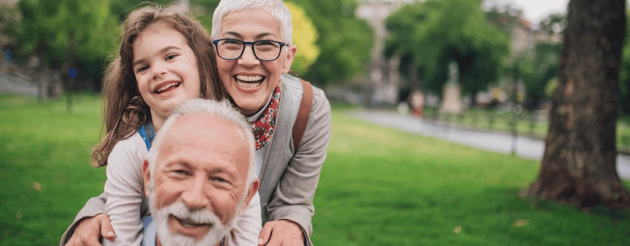 grandparents-smiling-with-granddaughter-at-a-park